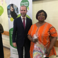 The MP of Tameside at the Diversity Matters event. Jonathan Reynolds and Tosin standing for a picture and behind them is a diversity matters stand poster
